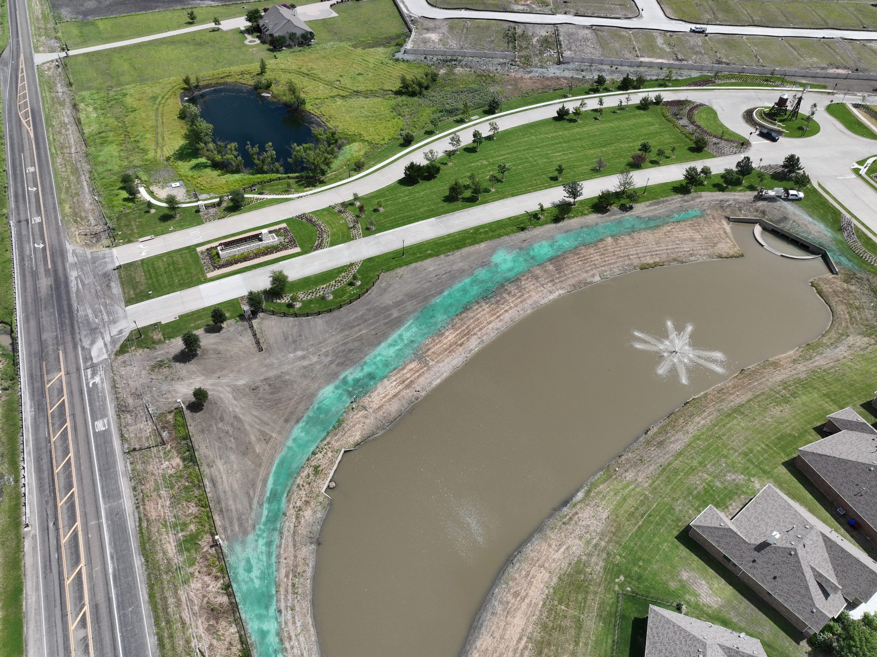 Aerial view of a landscaped parkway, aerated pond, and pocket park along the entry at Clearview Ranch in Royse City, Texas