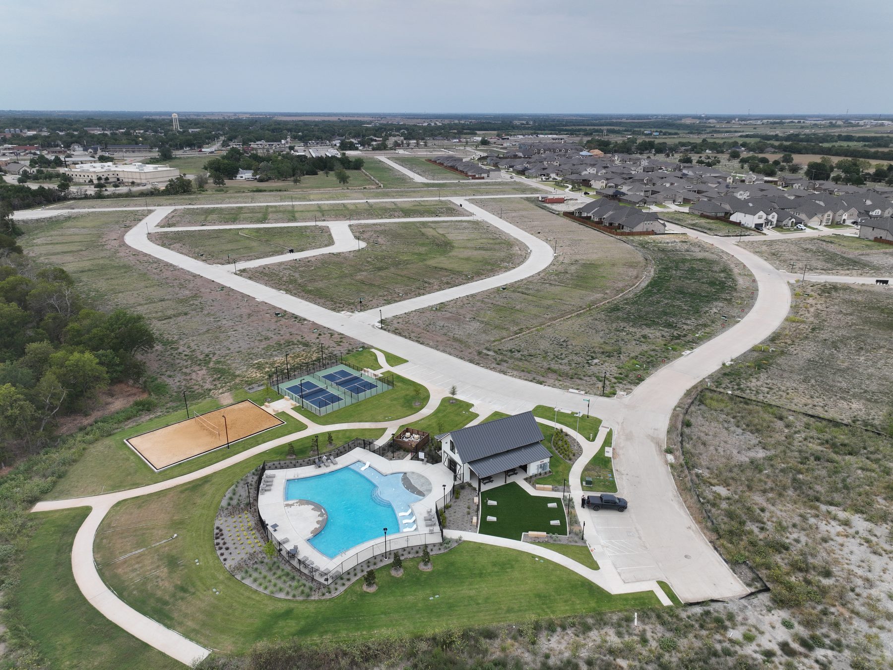 Aerial view of the amenity center at Liberty Crossing in Royse City, Texas, set among the finished street network with pool, courts, and sand volleyball