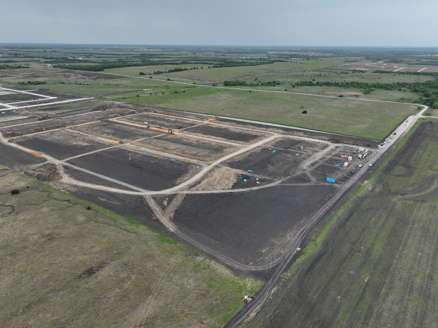 Aerial view of excavators and earthmoving equipment cutting streets and building pads at Cartwright Mays Phase 3A in Crandall, Texas
