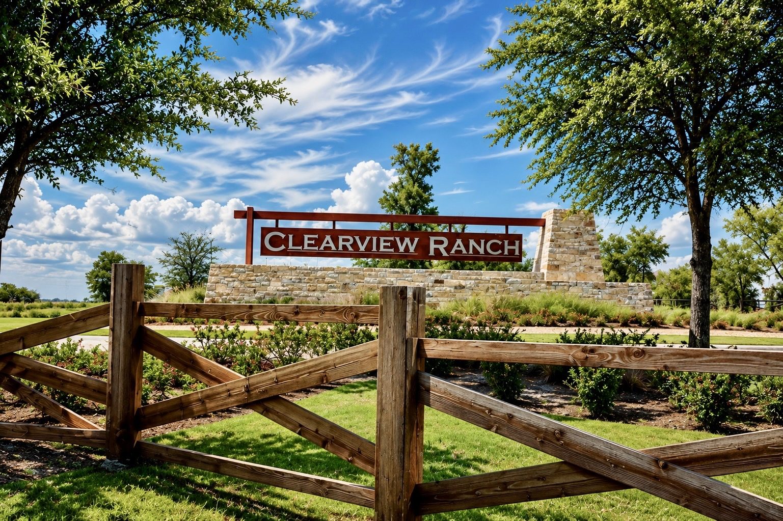 The Clearview Ranch stone entry sign in Royse City, Texas, framed by mature trees and a timber ranch rail fence
