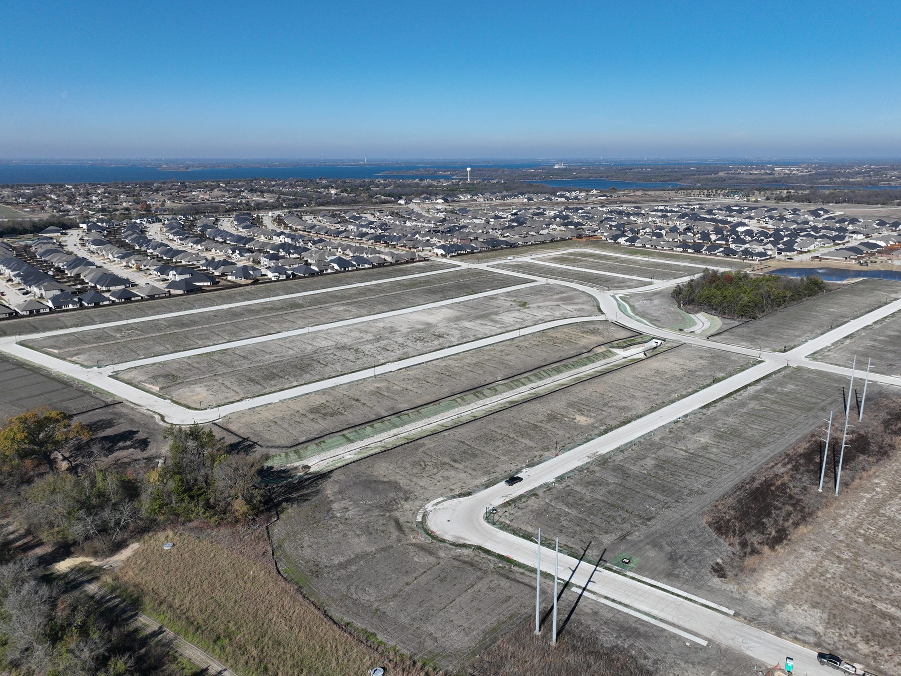 Aerial view of finished homesites and paved streets delivered at Elevon Section 1, Phase 4 in Lavon, Texas, with Lake Lavon on the horizon