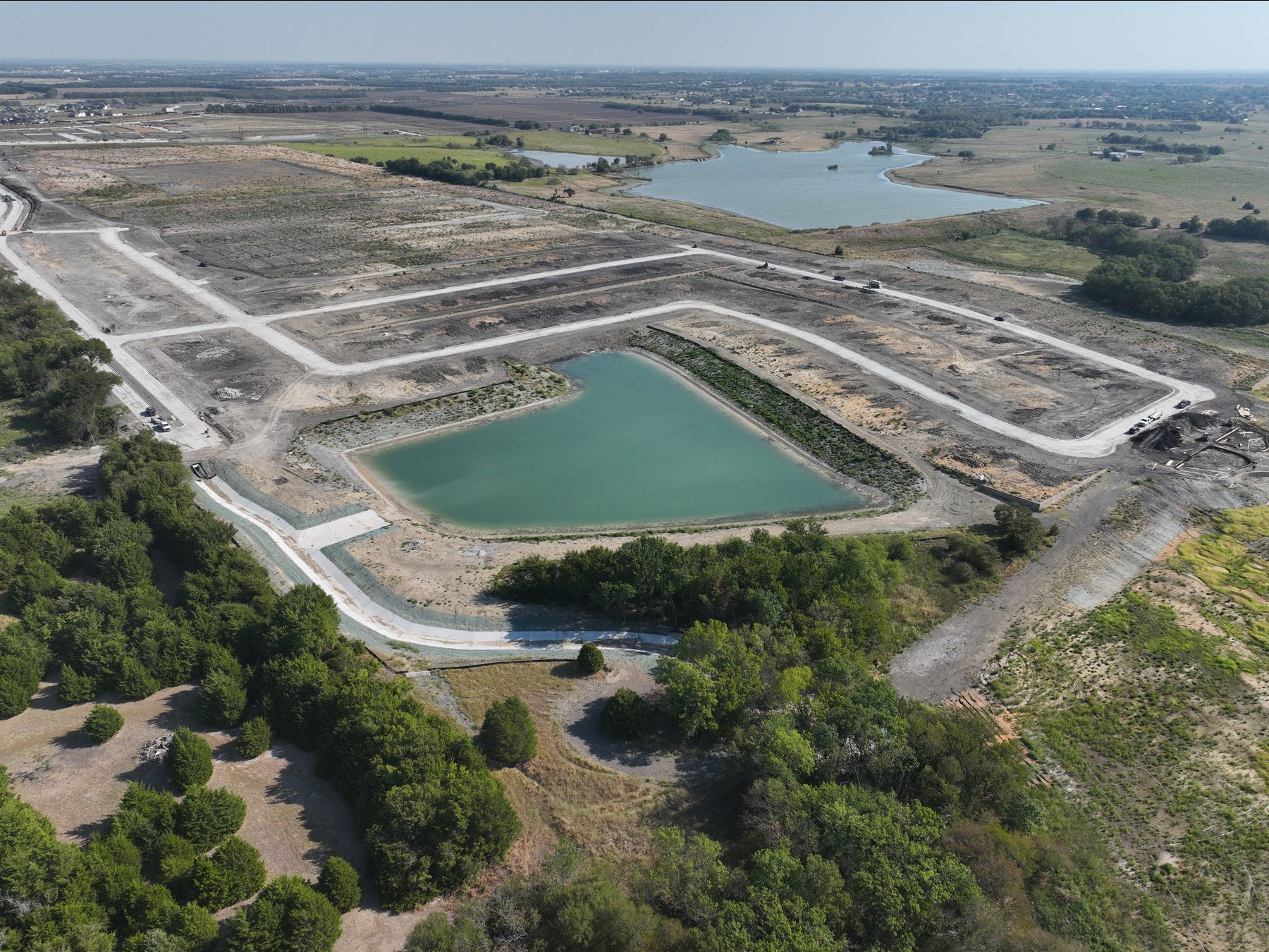 Aerial view of paved streets looping a detention pond at Elevon Section 5 in Lavon, Texas, with Lake Lavon beyond