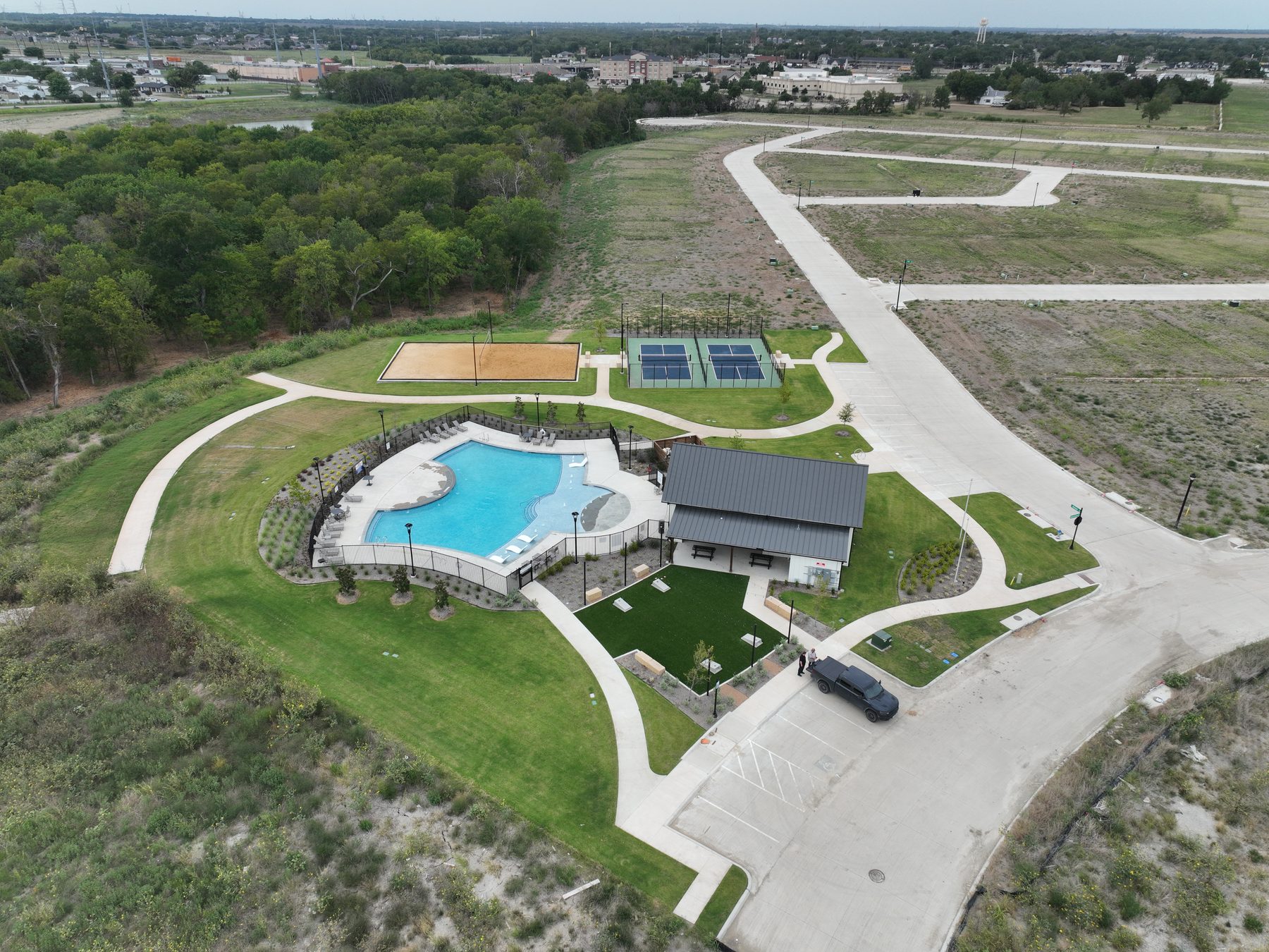 Aerial view of pickleball courts, sand volleyball, pool, and amenity building at Liberty Crossing in Royse City, Texas
