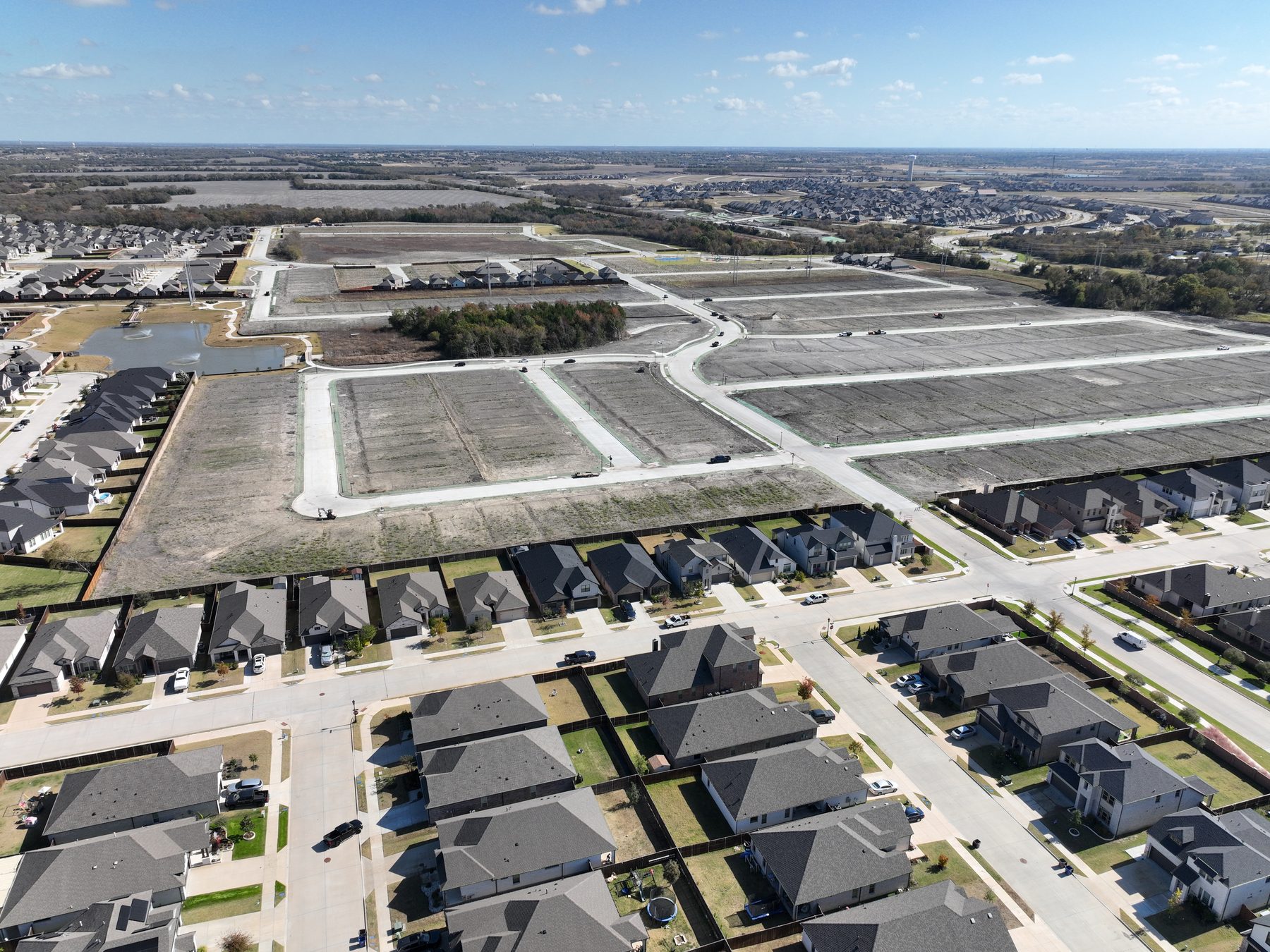 Aerial view of completed homes beside finished, still-vacant homesites at Elevon Phase 4 in Lavon, Texas, showing delivered lots waiting on the builder