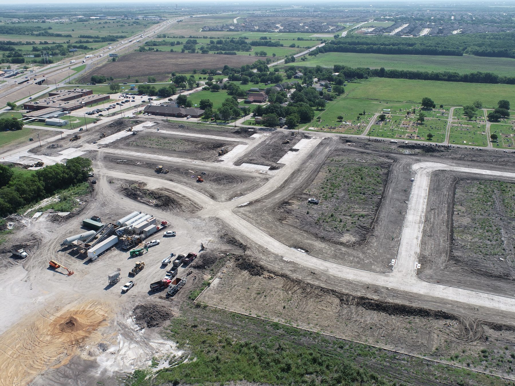 Aerial view of Liberty Crossing Phase 1 under construction in Royse City, Texas, with equipment and material trailers staged beside newly cut streets