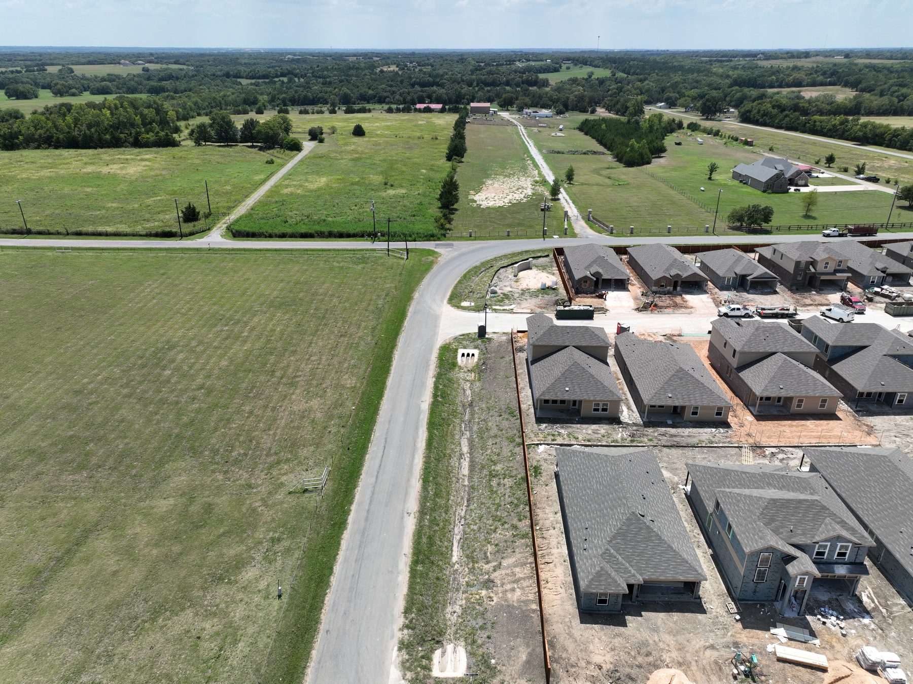 Aerial view of finished and newly framed homes along the street at Sweetwater Springs Phase 2 in Sherman, Texas