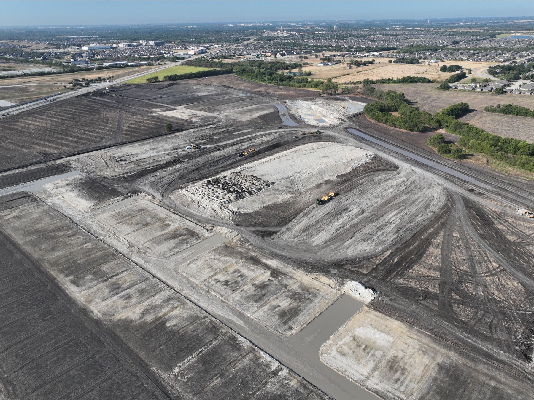 Aerial view of graded building pads, stockpiles and earthmoving equipment at The Preserve in Melissa, Texas