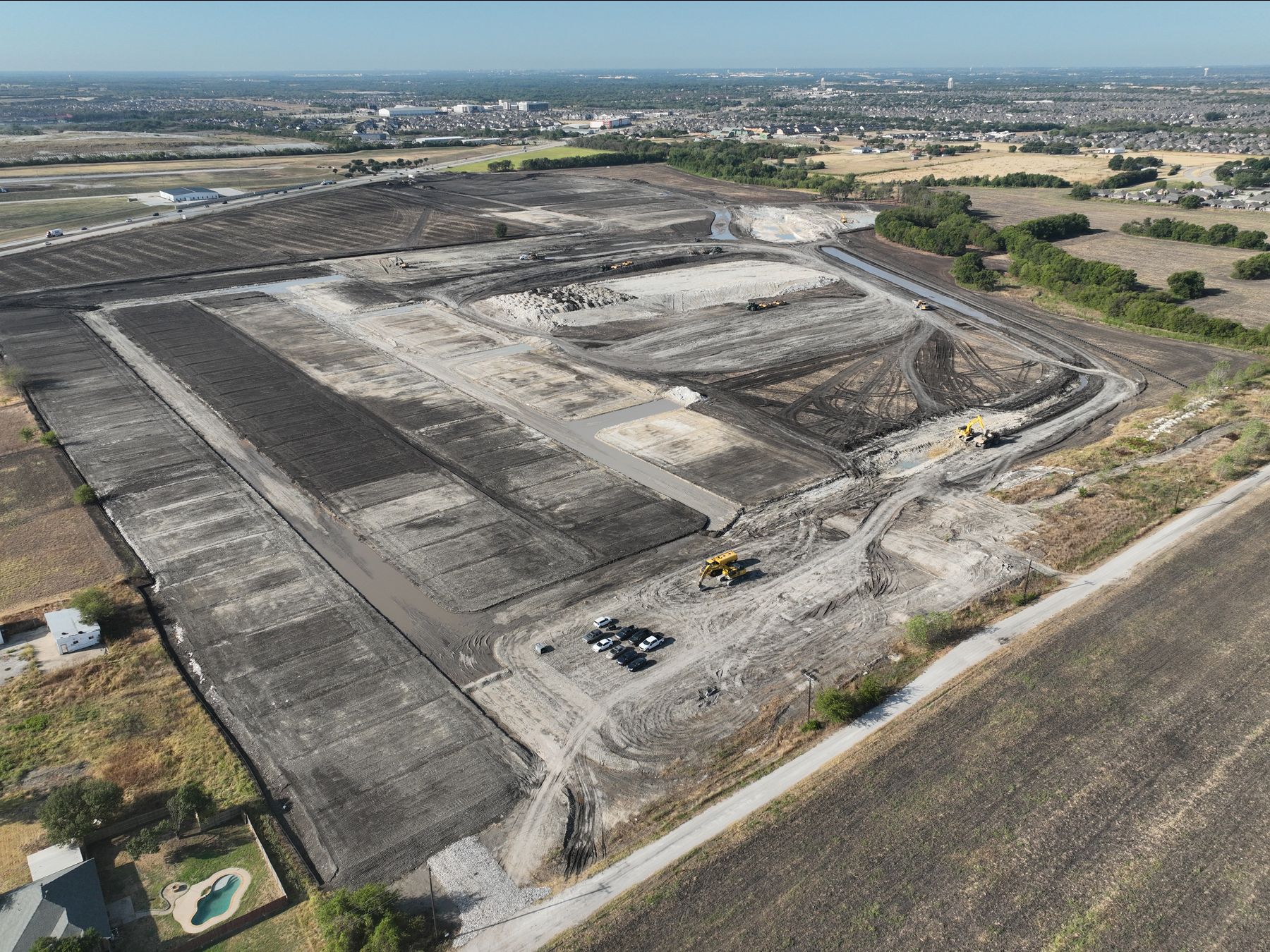 Aerial view of mass grading and new street cuts across The Preserve in Melissa, Texas, with established neighborhoods on the horizon