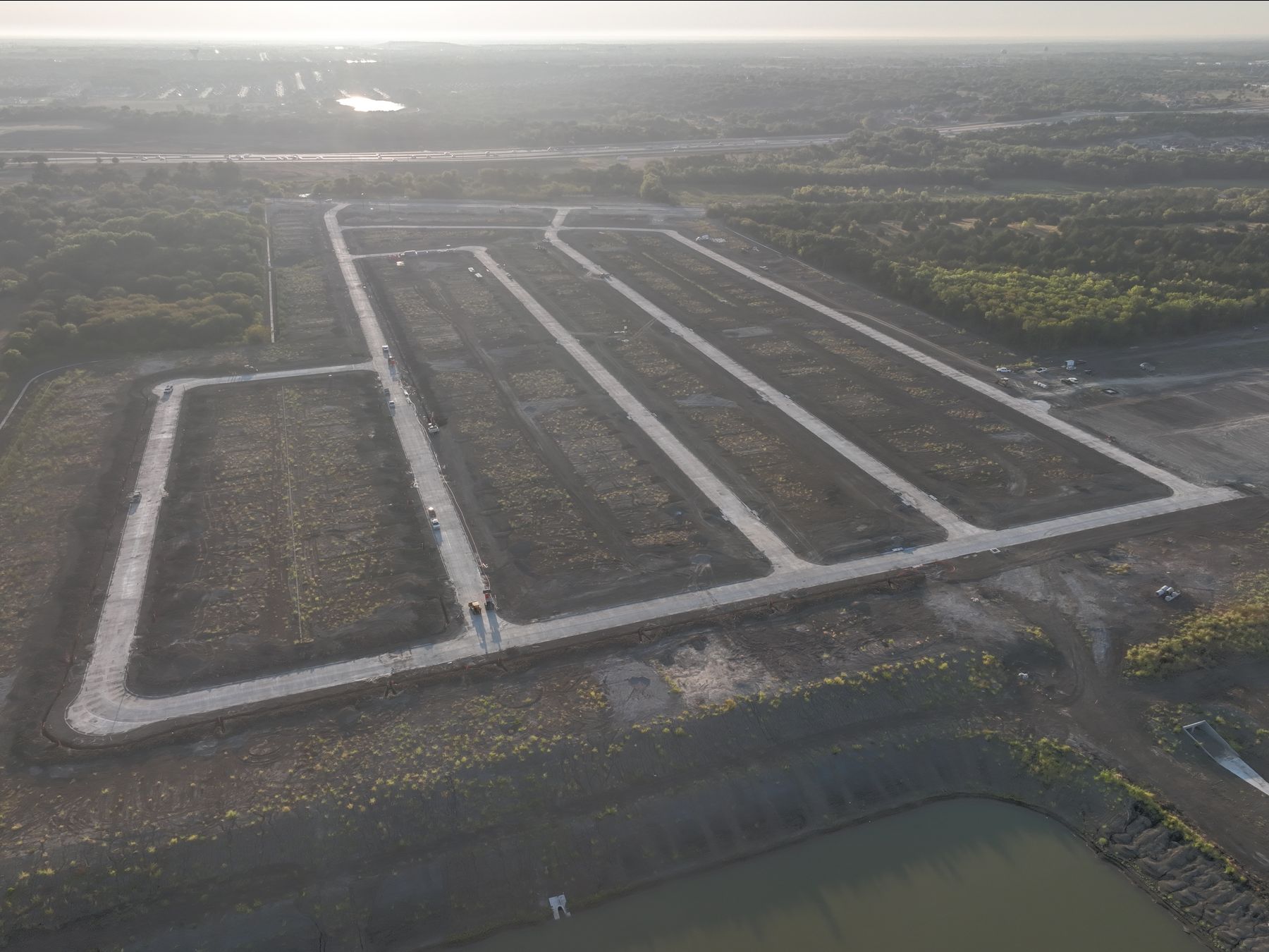 Aerial view of a finished grid of paved streets above a detention pond at Riverstone Estates in Melissa, Texas
