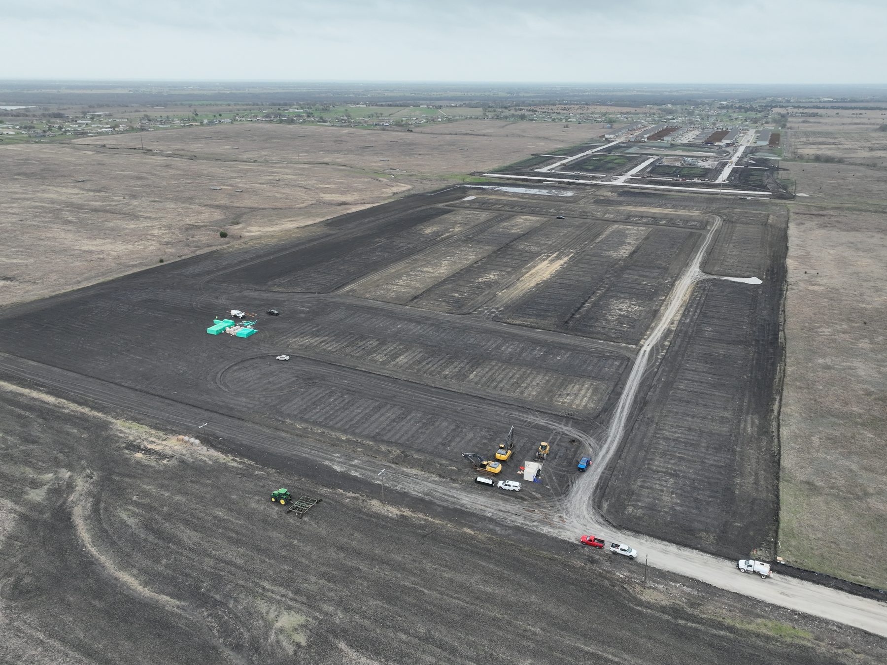 Aerial view of earthmoving equipment and haul trucks cutting streets and building pads at Cartwright Mays Phase 3A in Crandall, Texas