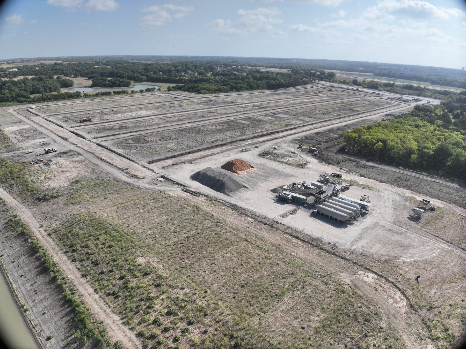 Aerial view of mass grading in progress at Riverstone Estates in Melissa, Texas, with equipment and staged pipe alongside cut pads