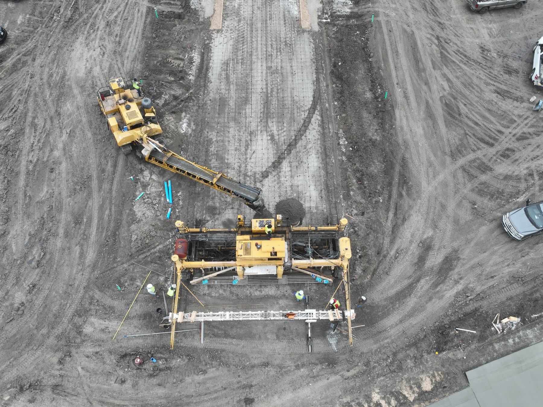 Close aerial view of a slipform paver and placer spreading concrete along a curb line at Arbor South in Princeton, Texas